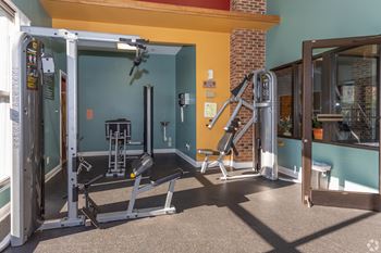 a gym with weights and a ladder and a glass door